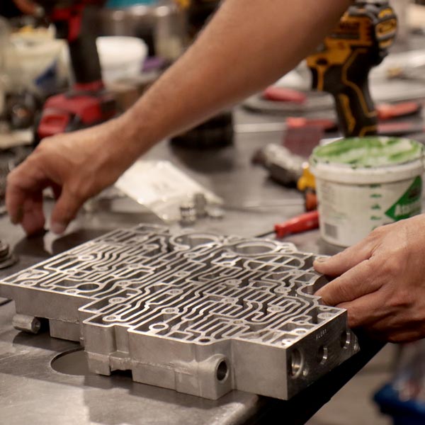 A man assembles a remanufactured transmission in a factory.
