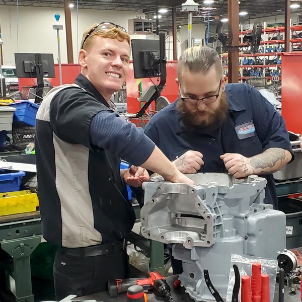 Two men work together to assemble a remanufactured transmission.