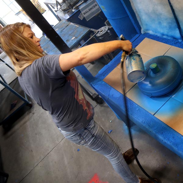 A woman sprays paint on a remanufactured transmission.