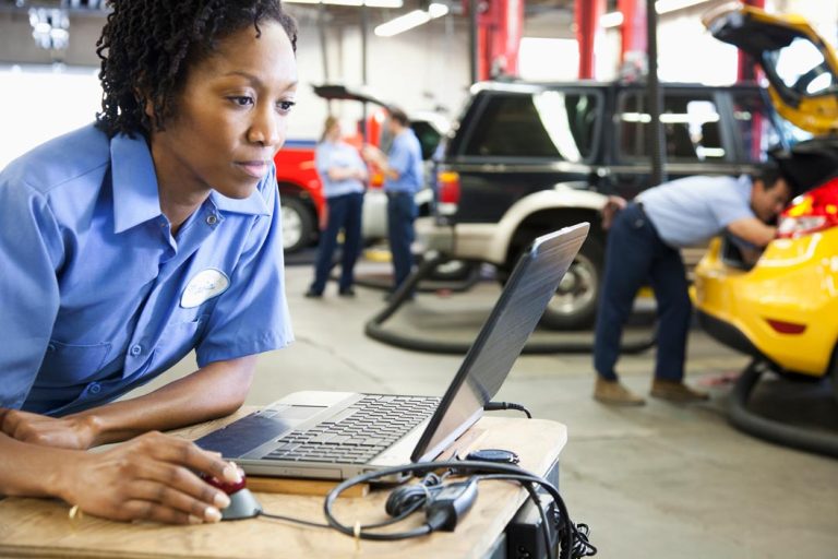 A female mechanic using a laptop.